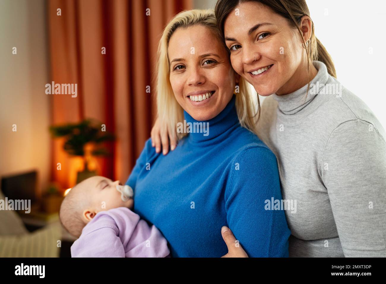 Happy lesbian couple with small baby at home portrait - LGBT family concept Stock Photo