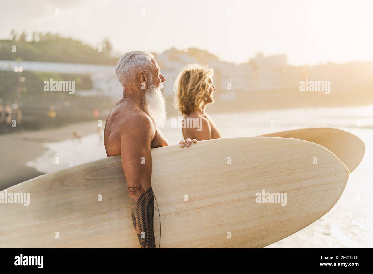 Happy fit surfers with different ages having fun surfing on tropical beach - Extreme sport lifestyle and friendship concept Stock Photo