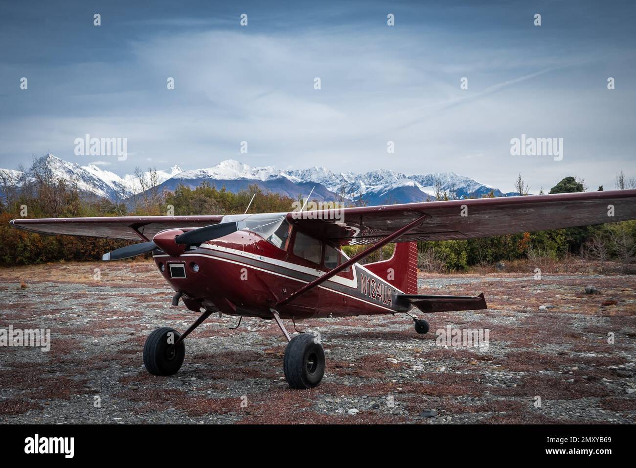 A Cessna Skywagon aircraft sitting on a dirt field near a glacier in Alaska Stock Photo