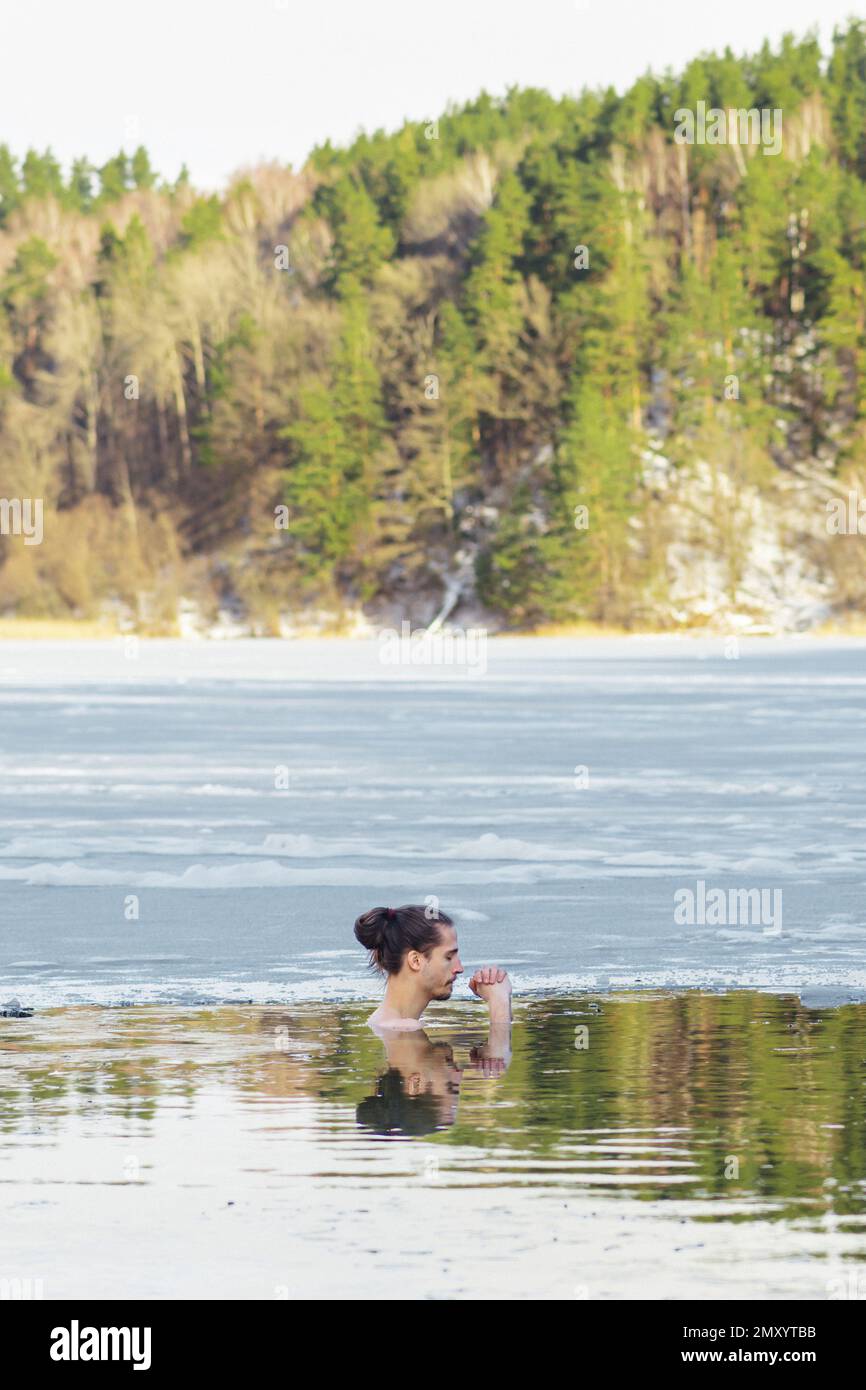 Handsome boy or man ice bathing in the cold water of a lake. Wim Hof