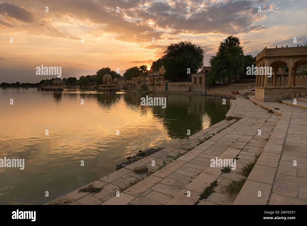 Beautiful sunset at Gadisar lake, Jaisalmer, Rajasthan, India. Setting sun and colorful clouds in the sky with view of the Gadisar lake. Stock Photo