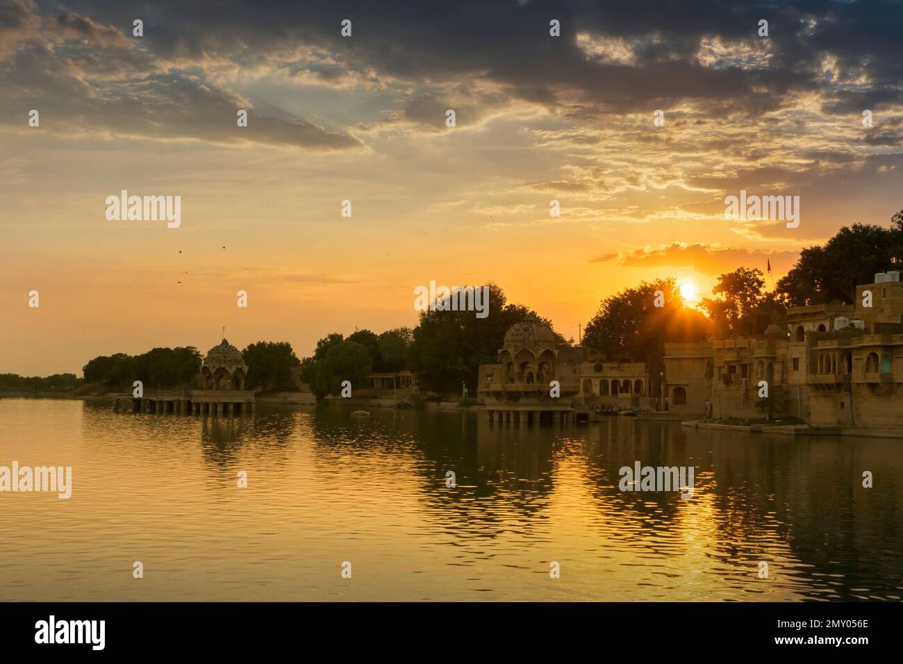 Beautiful sunset at Gadisar lake, Jaisalmer, Rajasthan, India. Setting sun and colorful clouds in the sky with view of the Gadisar lake. Stock Photo