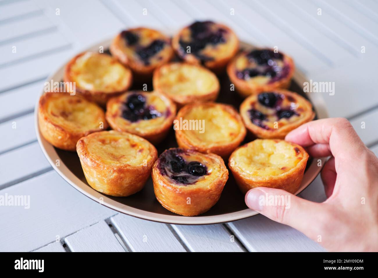 Hand holding Belem cakes or Pasteis de Belem, Portuguese pastel de Nata