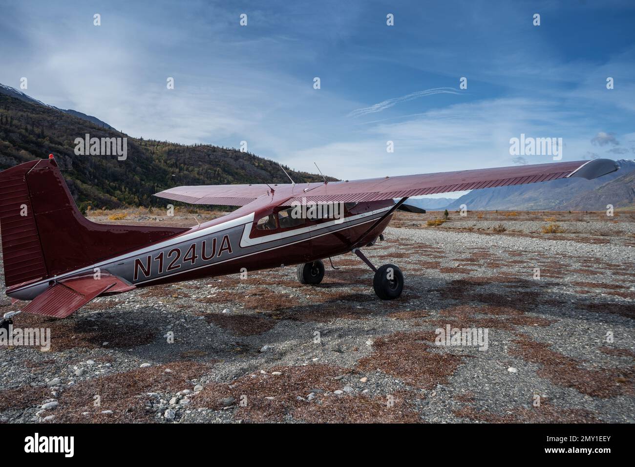 A Cessna Skywagon parked on the field with mountains and the blue sky in the background Stock Photo