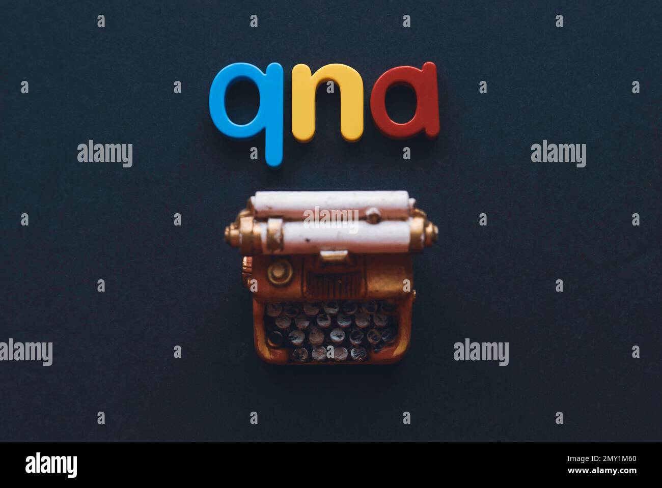 Questions and answers concept. Alphabet qna and miniature typewriter on dark background. Stock Photo