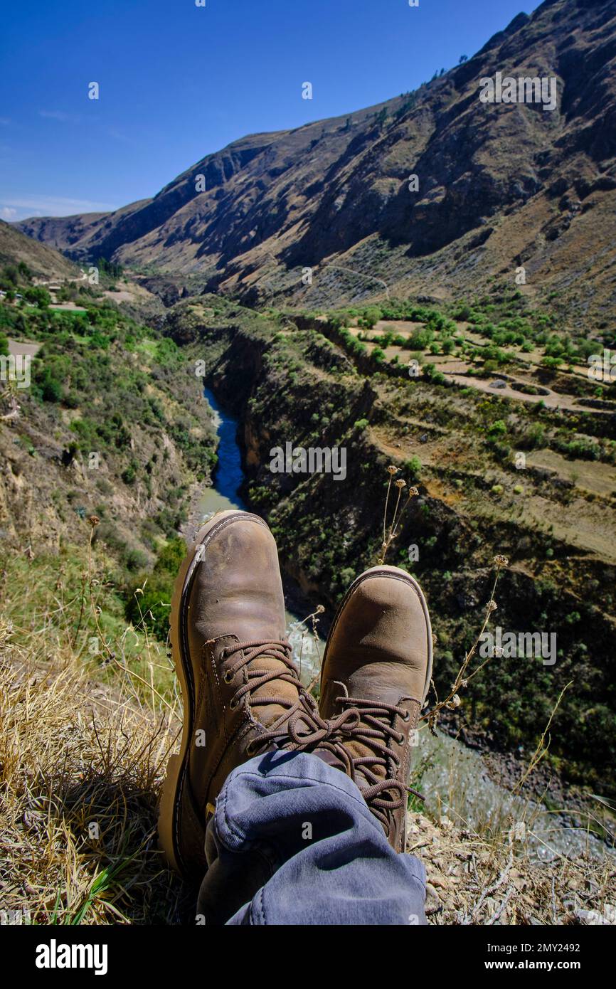Arid landscape of mountains, mountains, grasslands, and sparse or bushy vegetation with feet and shoes of a tourist in the foreground. South of the Ma Stock Photo