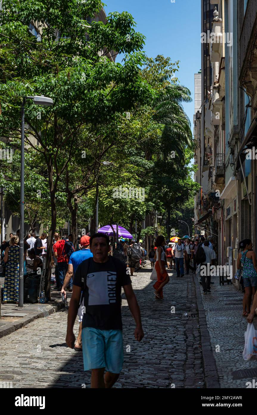 Lots of pedestrians walking around on Uruguaiana street public market and nearby tall buildings in Centro district under summer morning clear blue sky Stock Photo