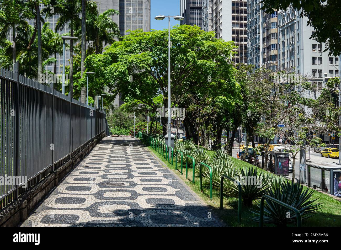 The empty cobblestone pavement sidewalk nearby BNDES headquarters building and Petrobras building in Centro district under summer sunny clear sky. Stock Photo