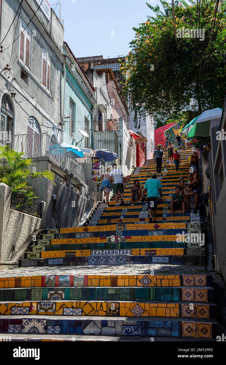 The middle section of decorated Selaron Steps in Santa Teresa district nearby Ladeira de Santa Teresa street and some colourful houses under sunny day. Stock Photo