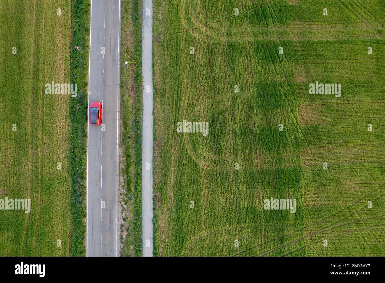 Drone aerial of Red car traveling on a scenic rural road. Countryside with green agriculture field. Cyprus Stock Photo