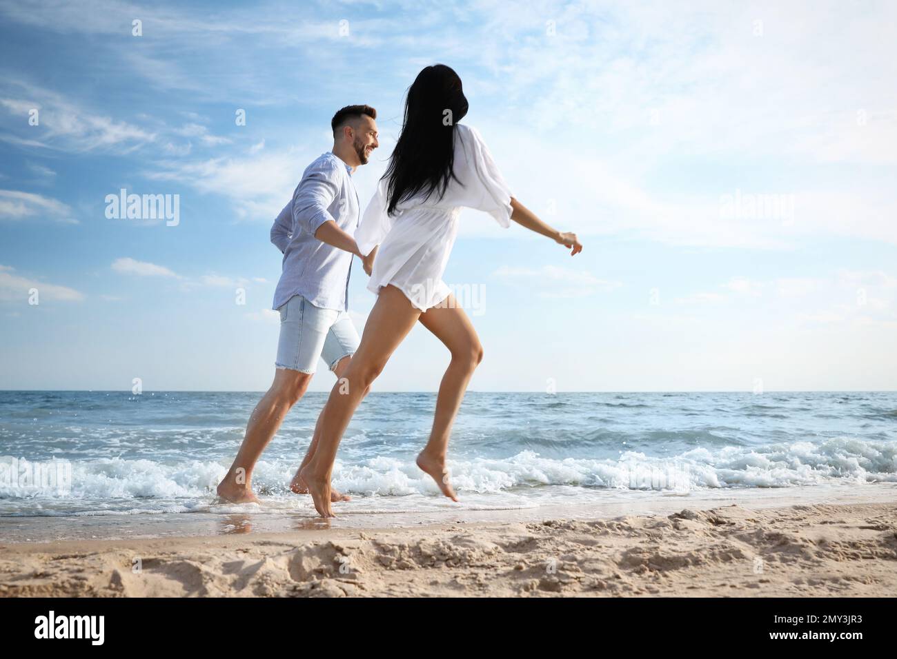 Happy young couple running together on beach Stock Photo - Alamy