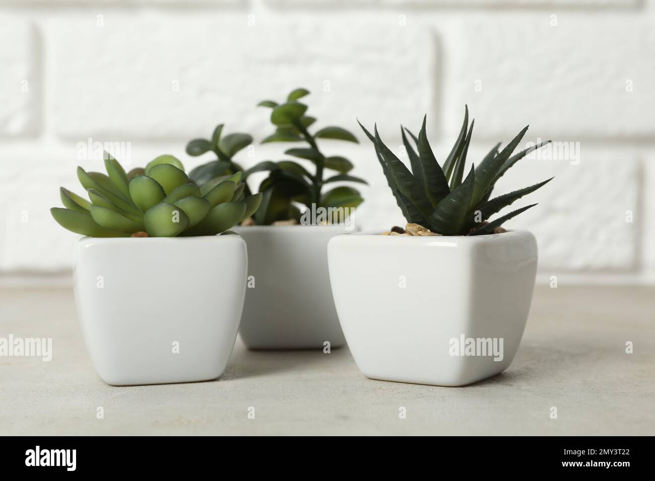 Beautiful artificial plants in flower pots on grey stone table near