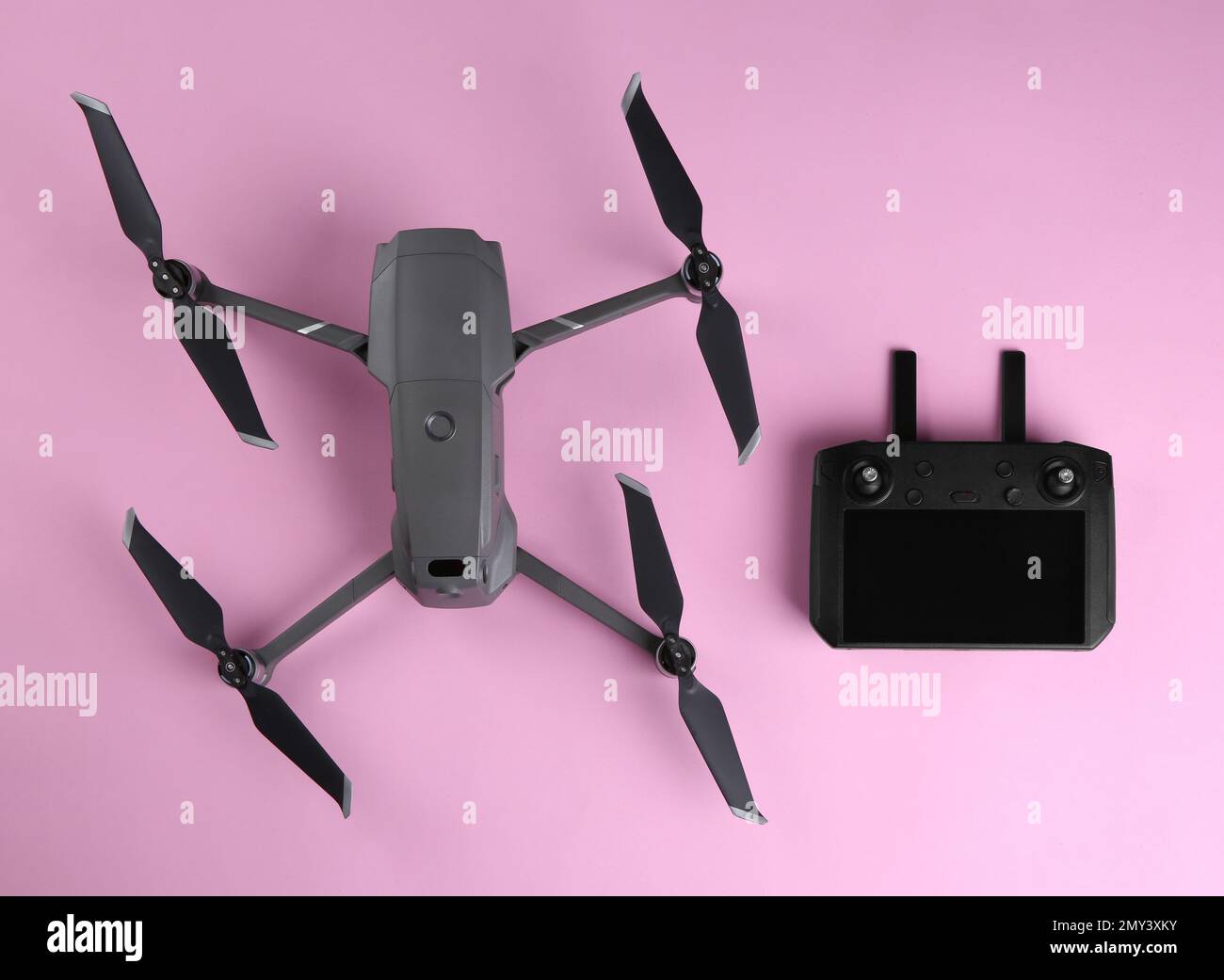 Modern drone with controller on pink background, flat lay Stock Photo