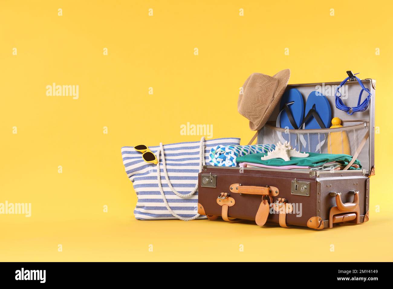 Bag and packed vintage suitcase with different beach objects on orange ...