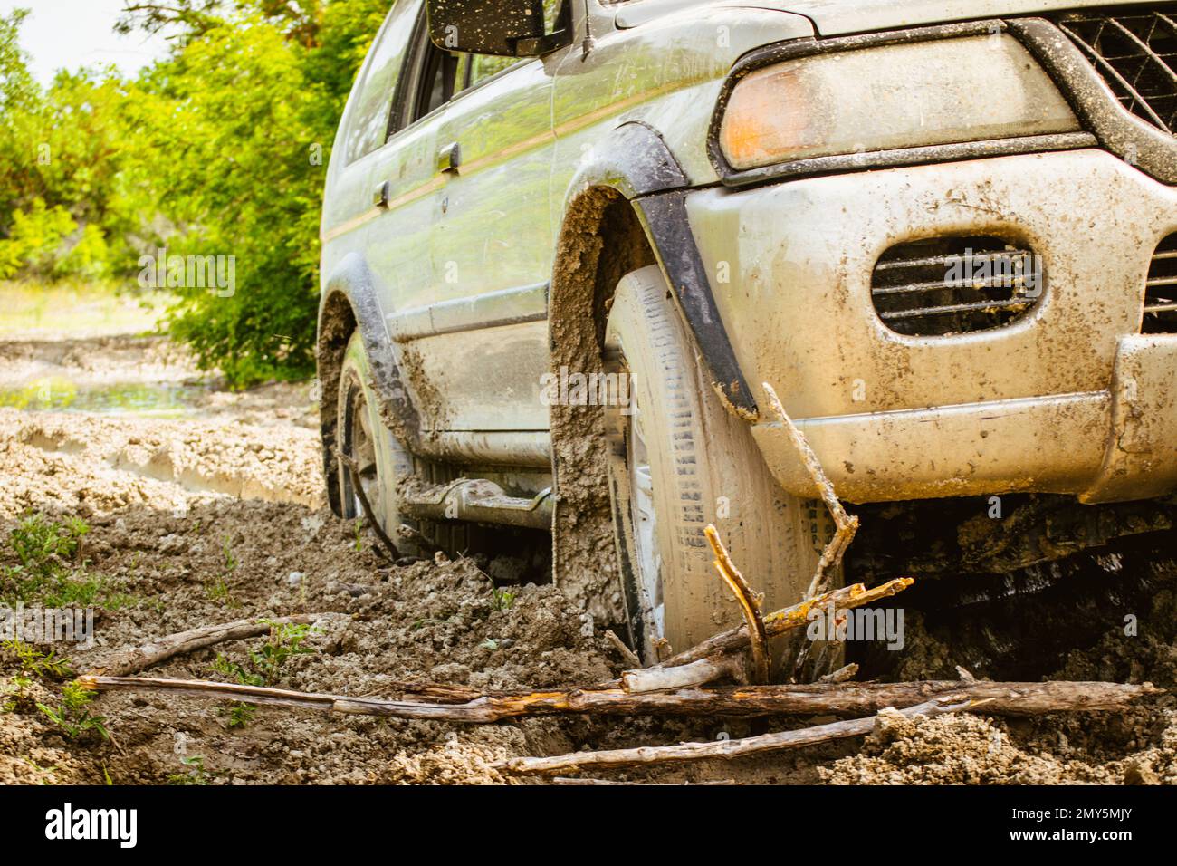 Close up view 4WD vehicle front wheel stuck in mud go backwards