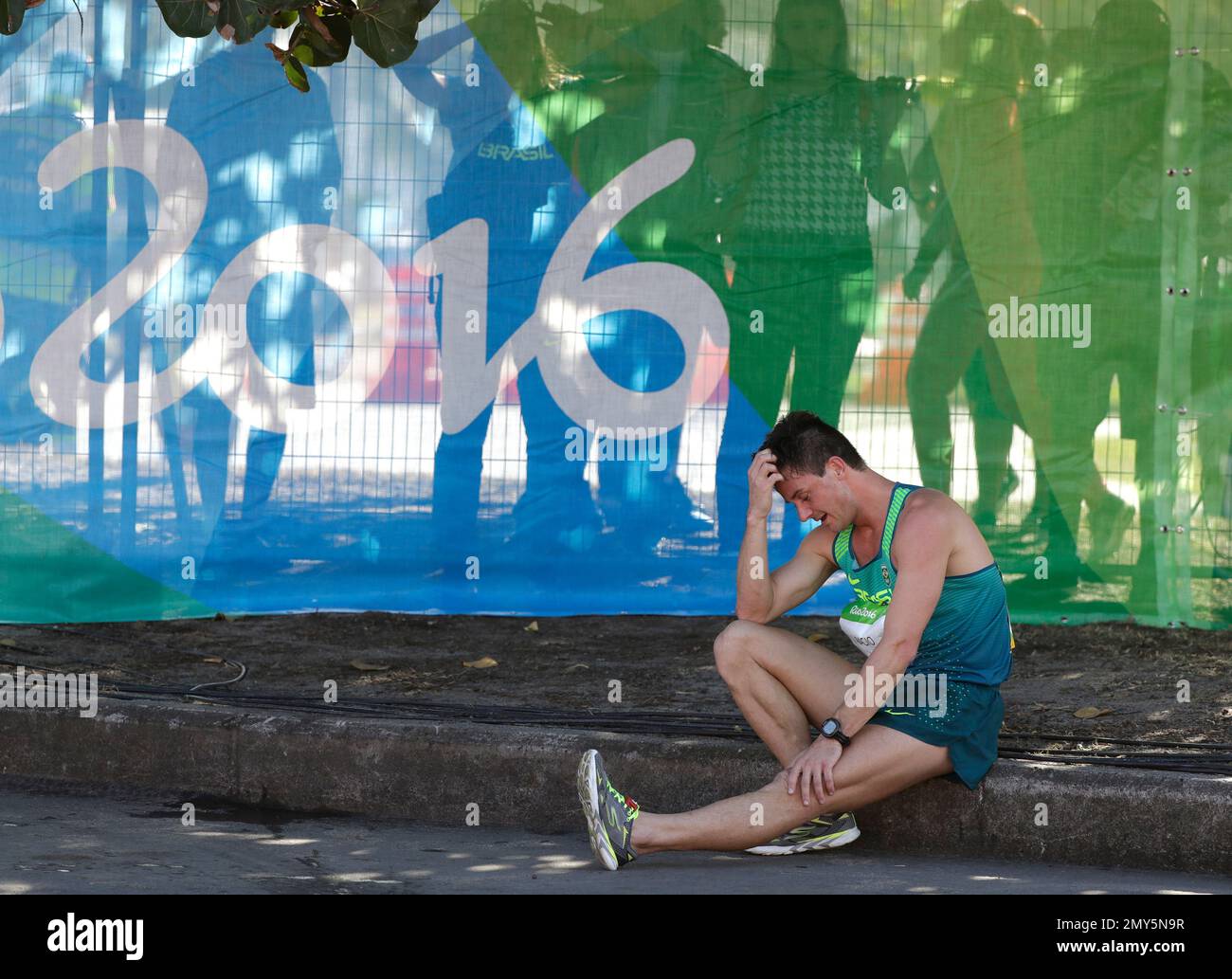 Spectators watch as Jose Alessandro Bagio, of Brazil, sits on the curb during the men's 20km race walk final at the 2016 Summer Olympics in Rio de Janeiro, Brazil, Friday, Aug. 12, 2016. Bagio did not finish the race. (AP Photo/Jae C. Hong) Stock Photo