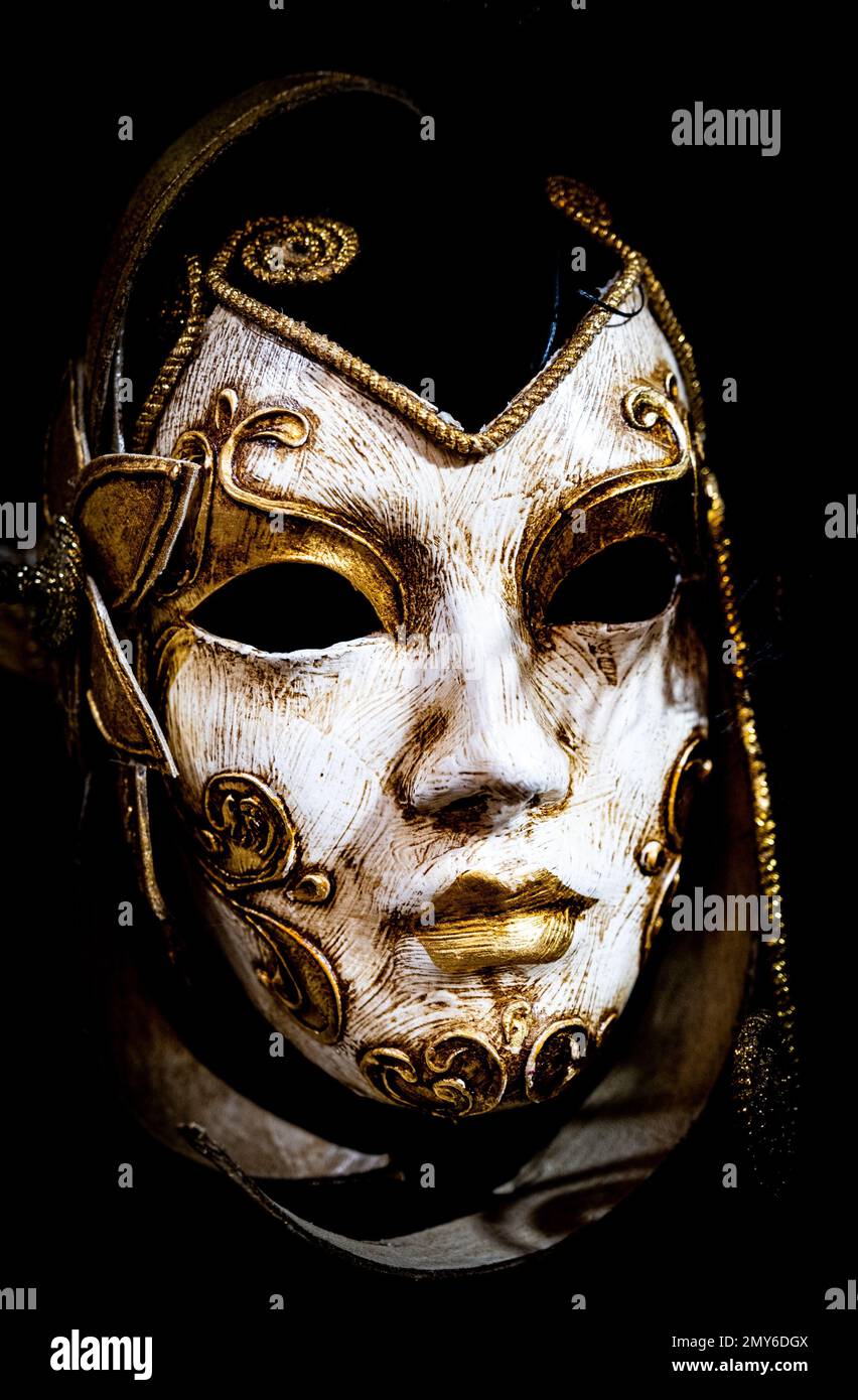 A vertical shot of the Venetian mask featuring a white face with gold ...