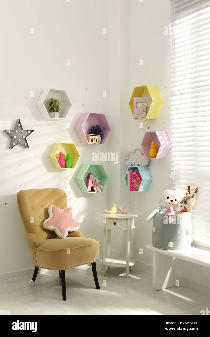 Hexagon shaped shelves on white wall in nursery. Interior design Stock