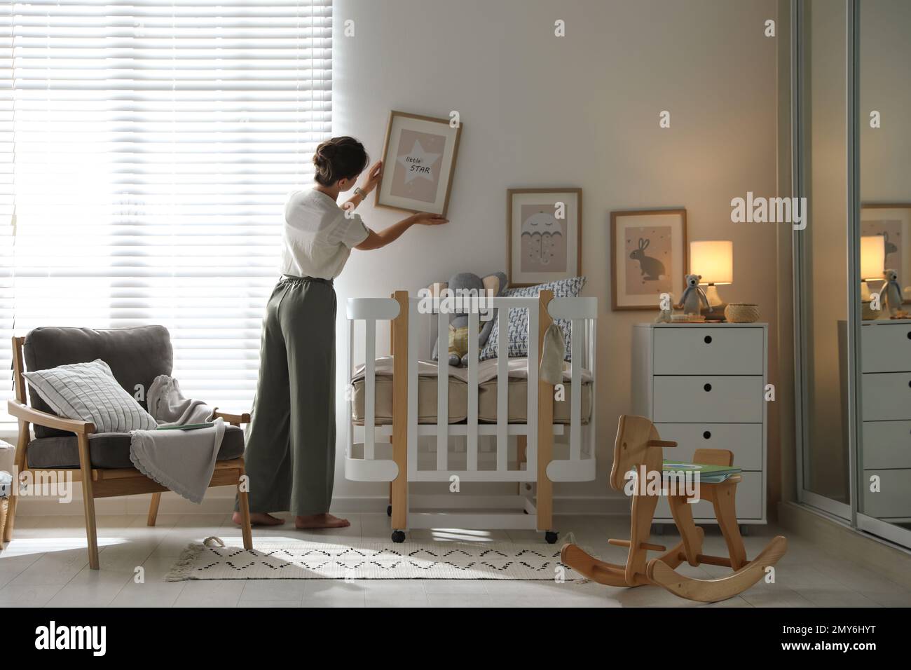 Decorator hanging picture on wall in baby room. Interior design Stock ...