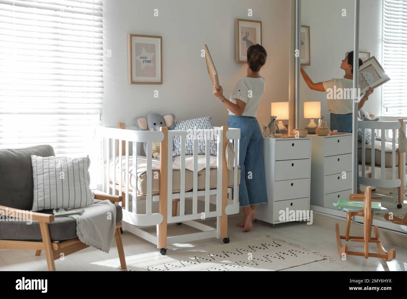 Decorator hanging pictures on wall in baby room. Interior design Stock ...