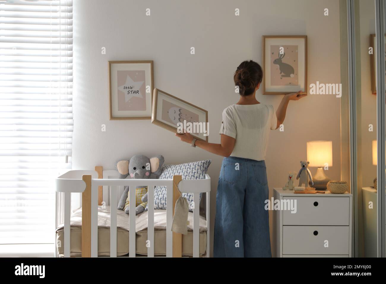 Decorator hanging pictures on wall in baby room. Interior design Stock ...