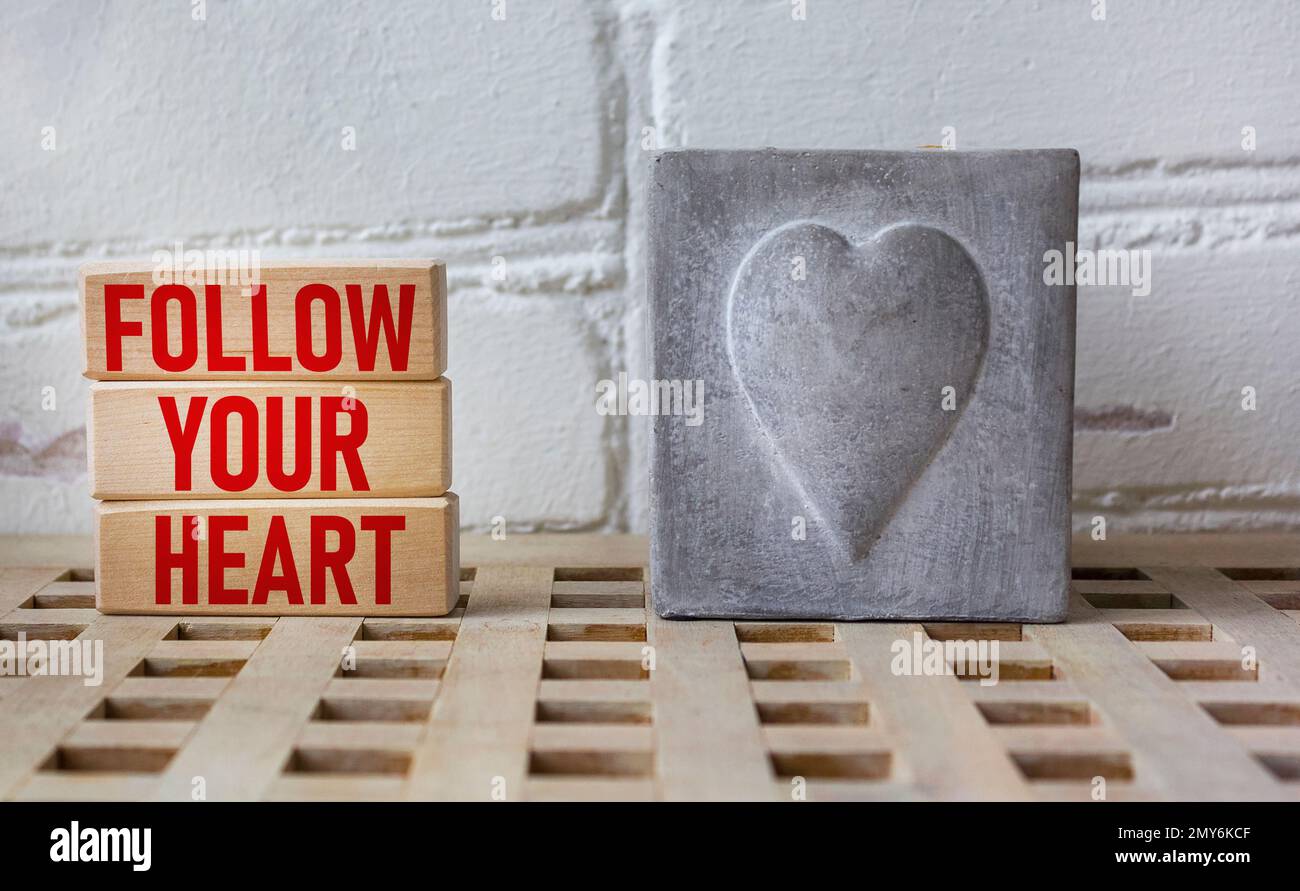 Follow your heart word written on a wooden block with a vintage heart candle. Stock Photo