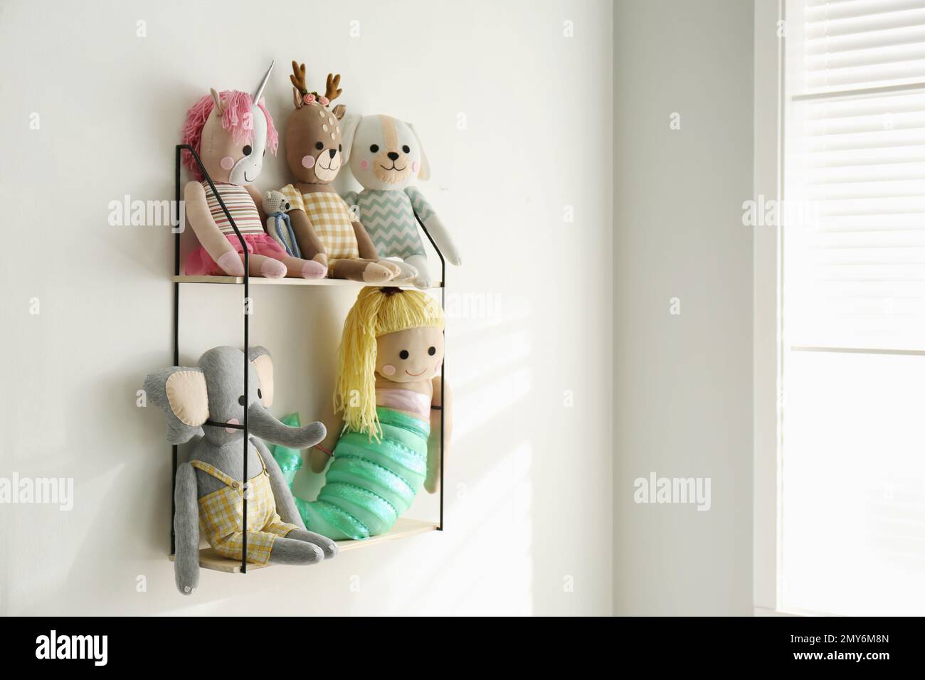 Shelf with cute toys on light wall indoors. Baby room interior element Stock Photo