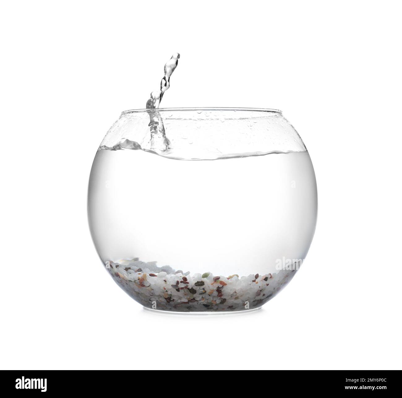 Splash of water in round fish bowl with decorative pebbles on white