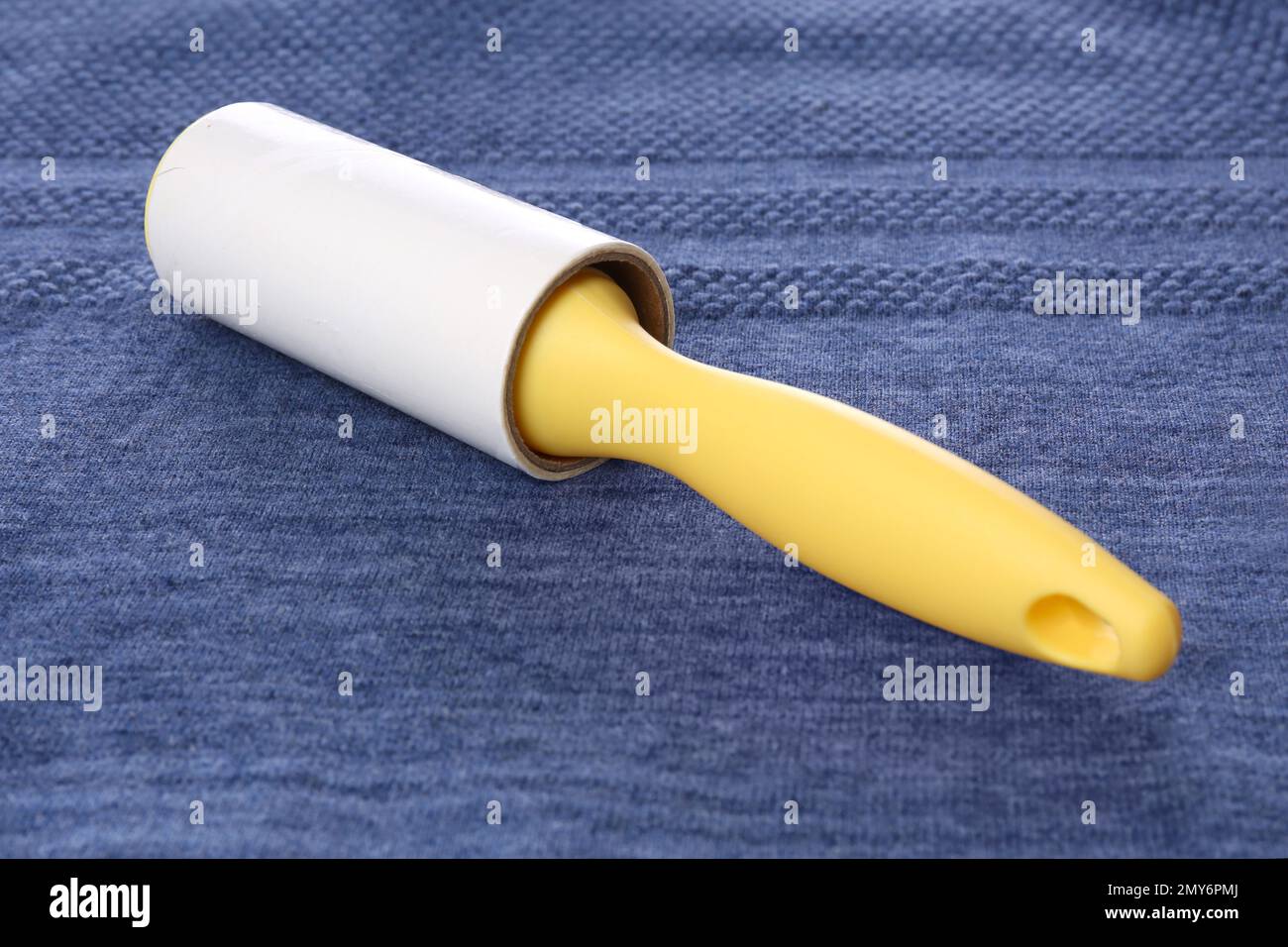 New lint roller with yellow handle on blue fabric Stock Photo