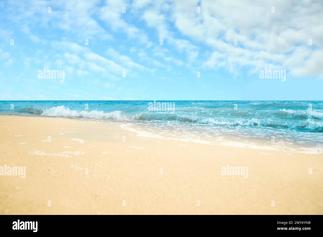 Ocean waves rolling on sandy beach under blue sky with clouds Stock ...