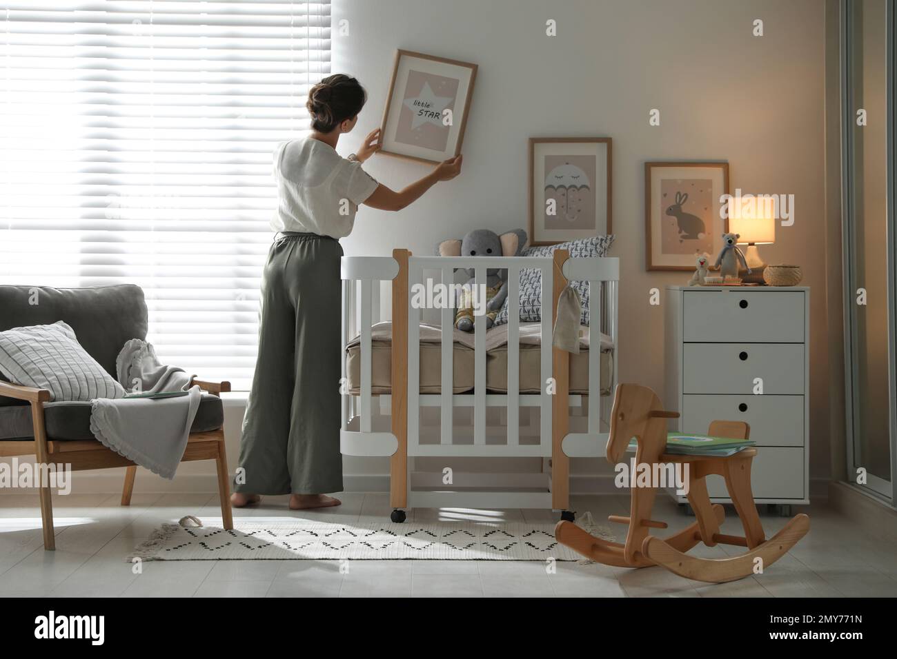 Decorator hanging picture on wall in baby room. Interior design Stock ...