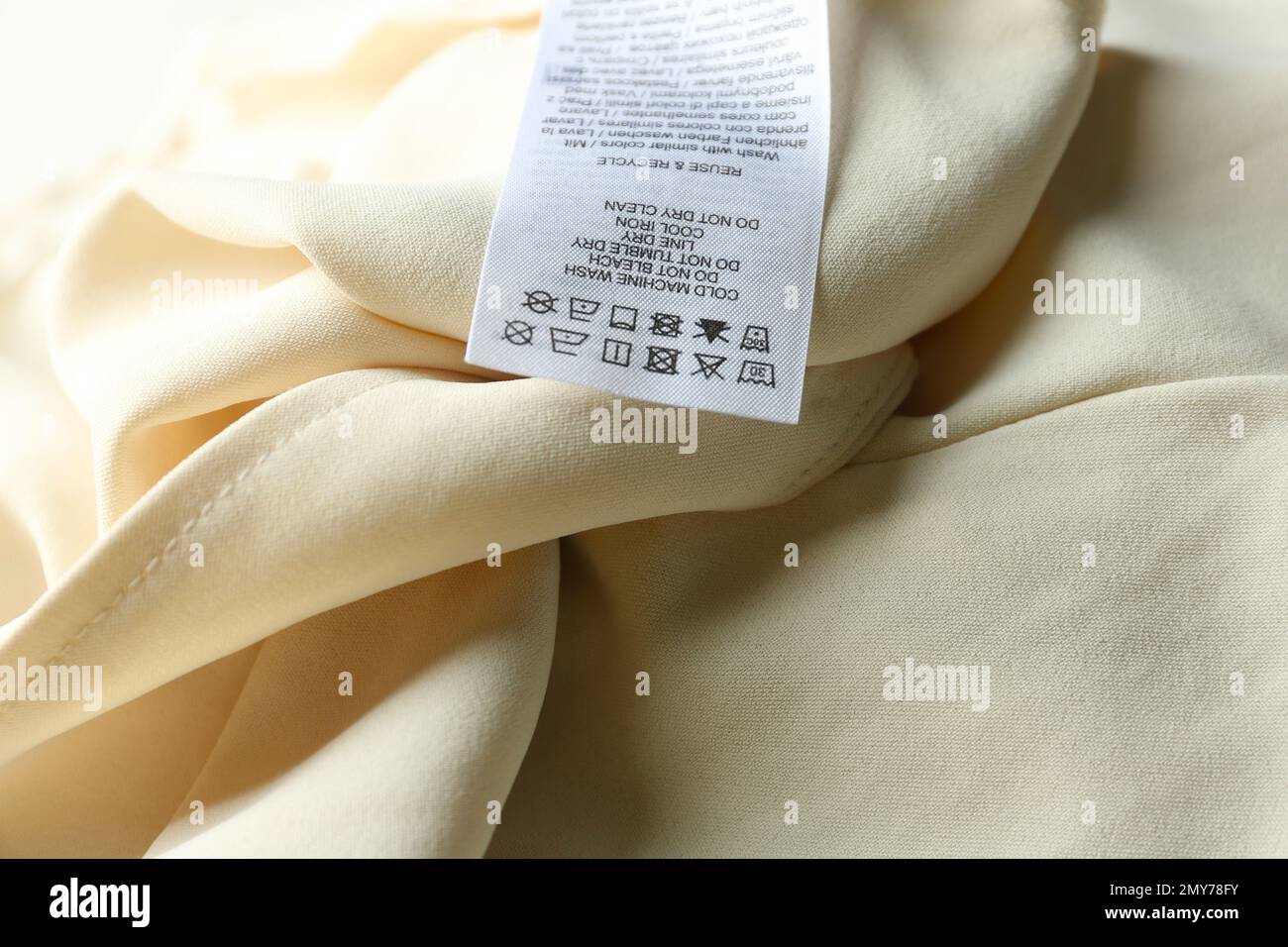 Clothing label with care instructions on beige garment, closeup Stock Photo