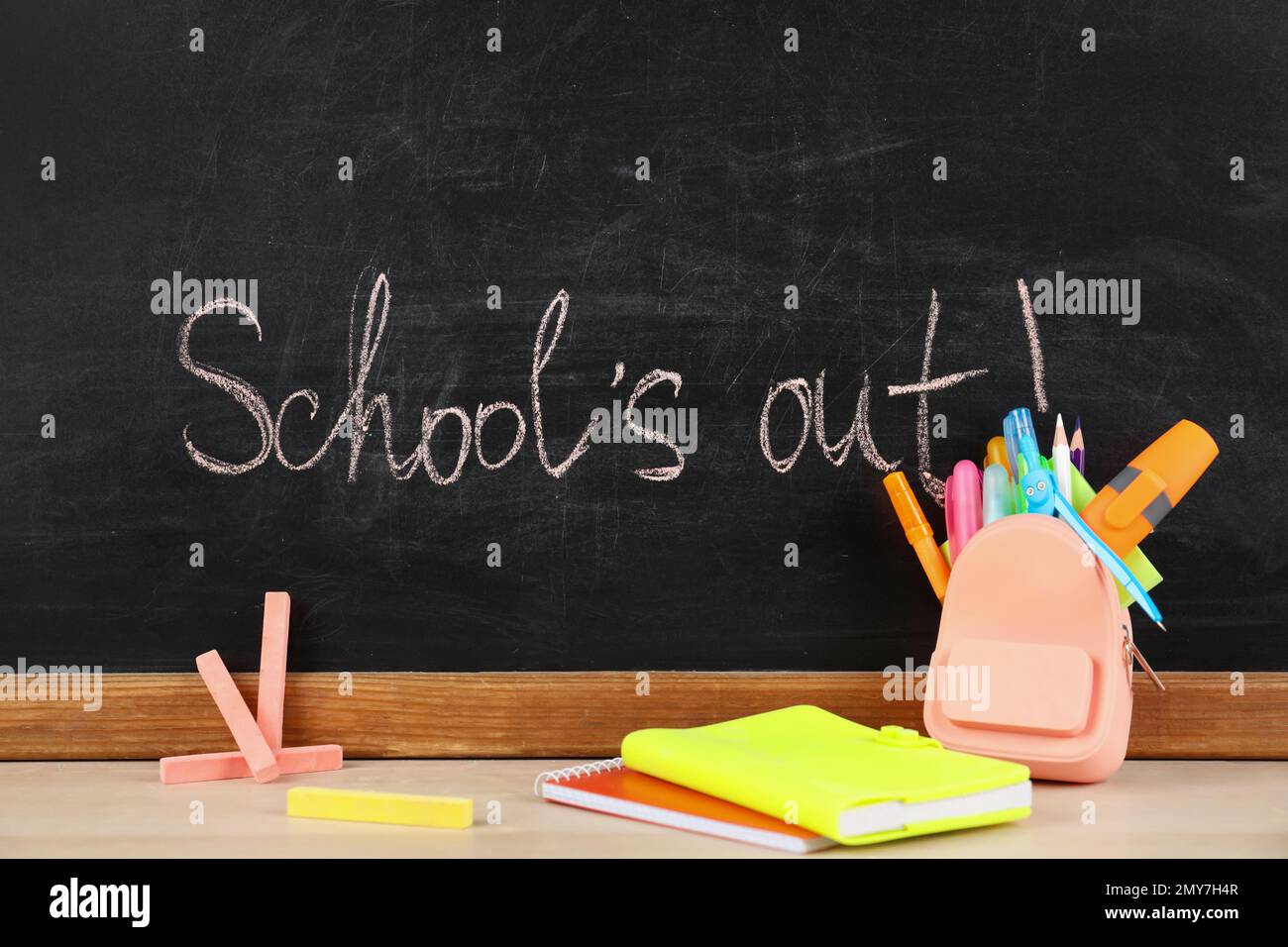 Pieces of color chalk and stationery on table near blackboard with text  School's Out. Summer holidays Stock Photo - Alamy
