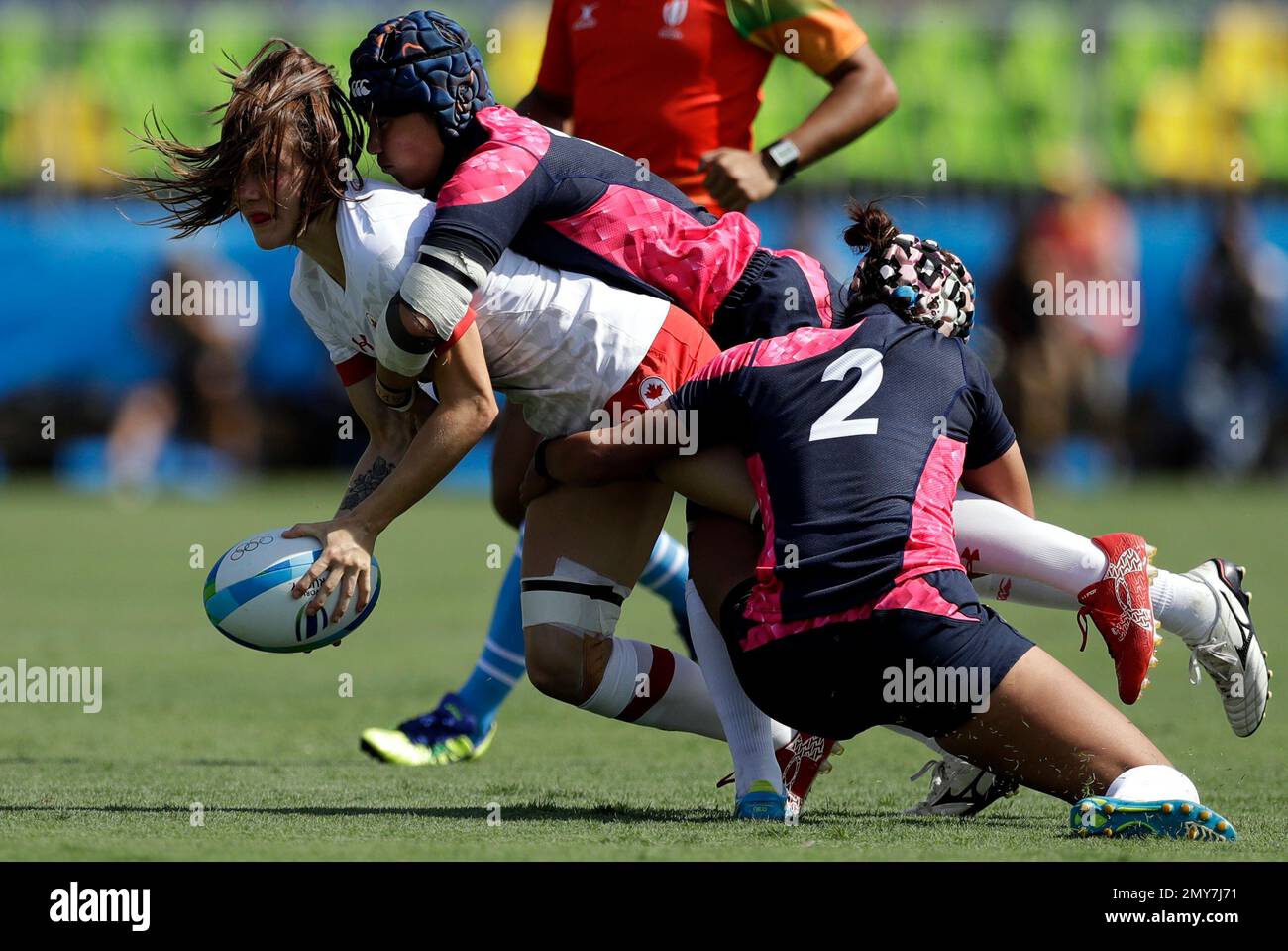Canadas Natasha Watcham-Roy, left, is tackled by Japans Makiko Tomita, right, and teammate during the womens rugby sevens match between USA and Fiji at the Summer Olympics in Rio de Janeiro, Brazil,