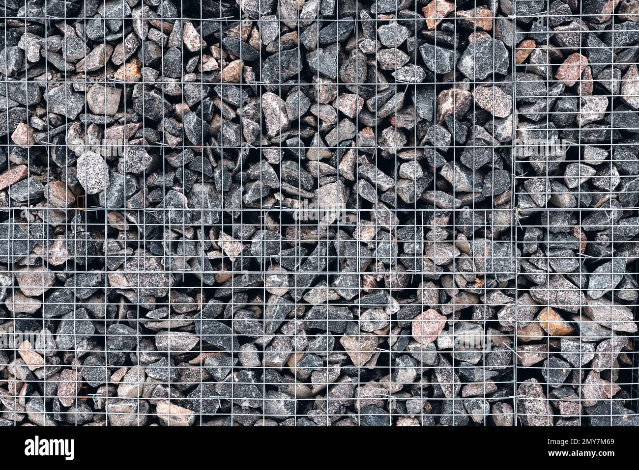 Stone wall made of whetstone in light gray, enclosed behind a metal
