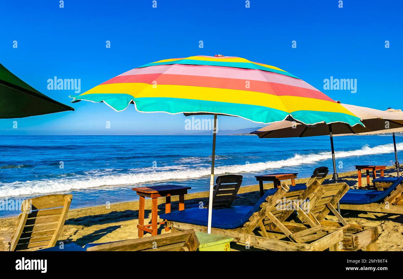 Parasols umbrellas sun loungers palms people rocks and waves at the