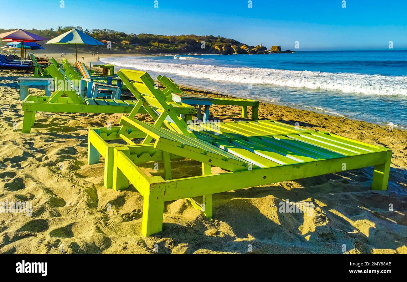 Parasols umbrellas sun loungers palms people rocks and waves at the