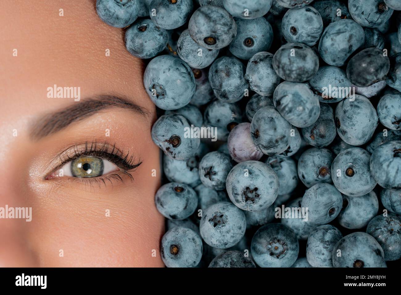 Happy woman face in eyewear fresh ripe berries - blueberries, strawberries, currant. Young girl covered with blackberry. Lady enjoying organic bilberr Stock Photo