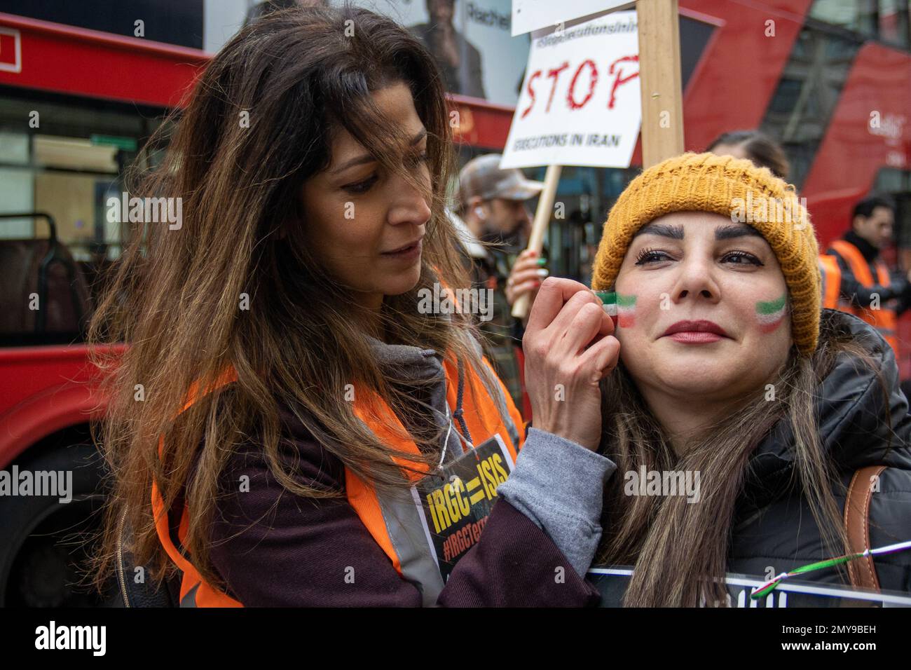 London, UK – Feb 4, 2023: A protester paints the Iranian flag colours on the face of another protester. About two hundred British-Iranians from different political backgrounds marched from Cavendish Square to Trafalgar Square, asking the UK government to put the Islamic Revolutionary Guard Corps of Iran on its terrorist list.  Credit: Sinai Noor/Alamy Live News Stock Photo