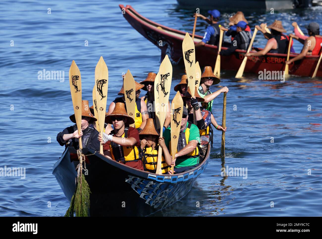 Members of a tribal canoe hold their paddle upright as they await the