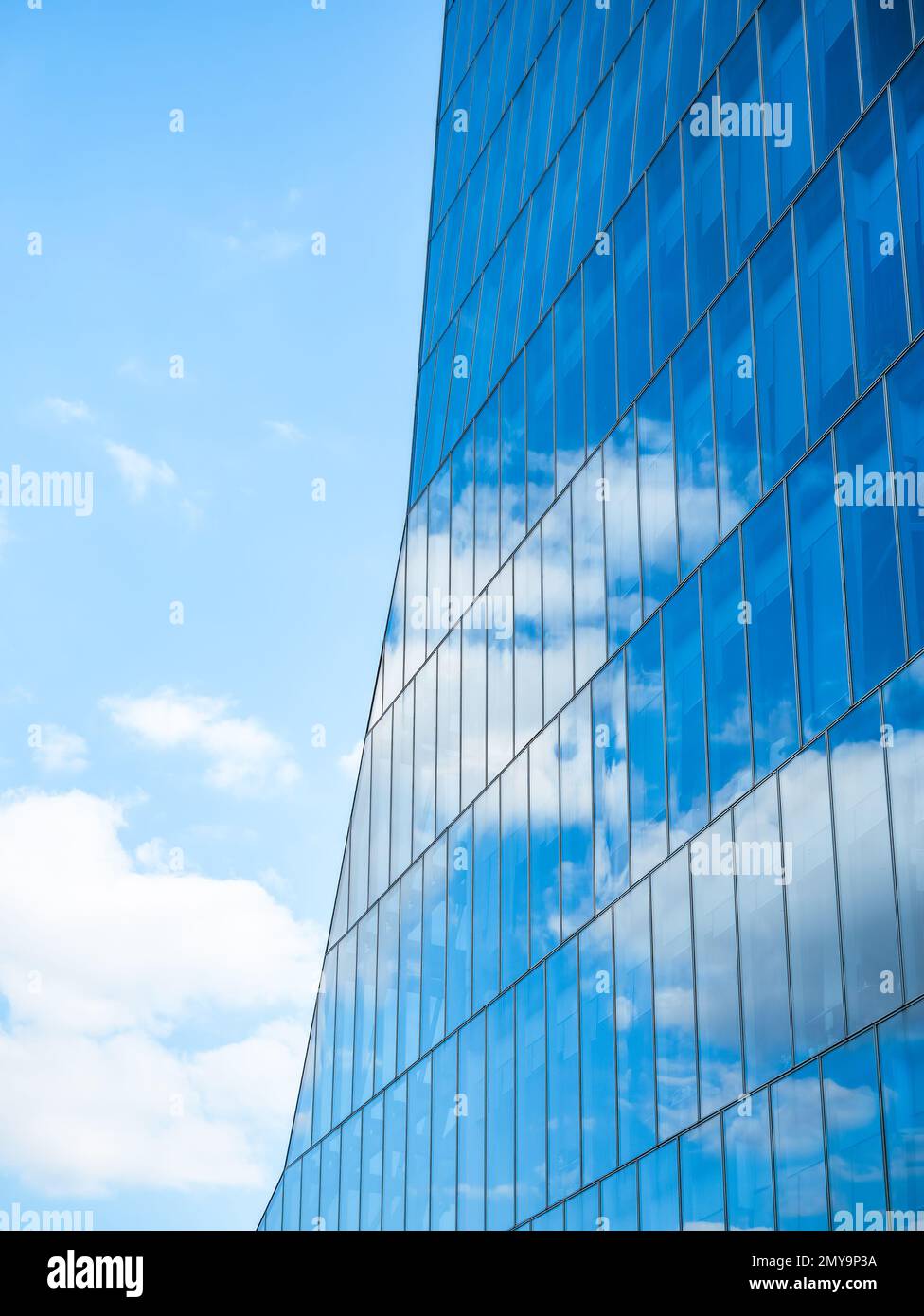 the sky with white clouds reflecting in the glass windows of a modern ...