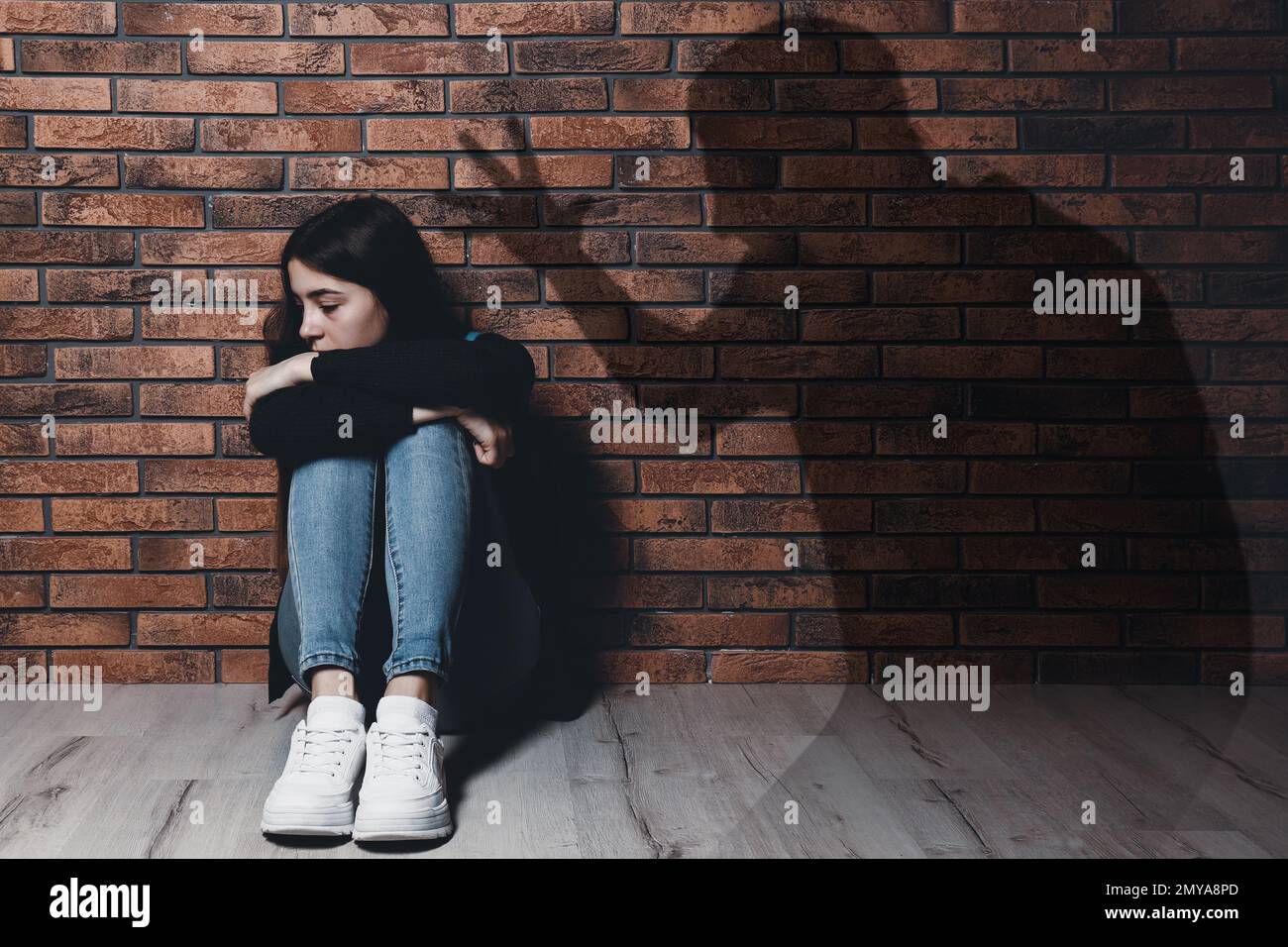 Child abuse. Father yelling at his daughter. Shadow of man on brick wall Stock Photo