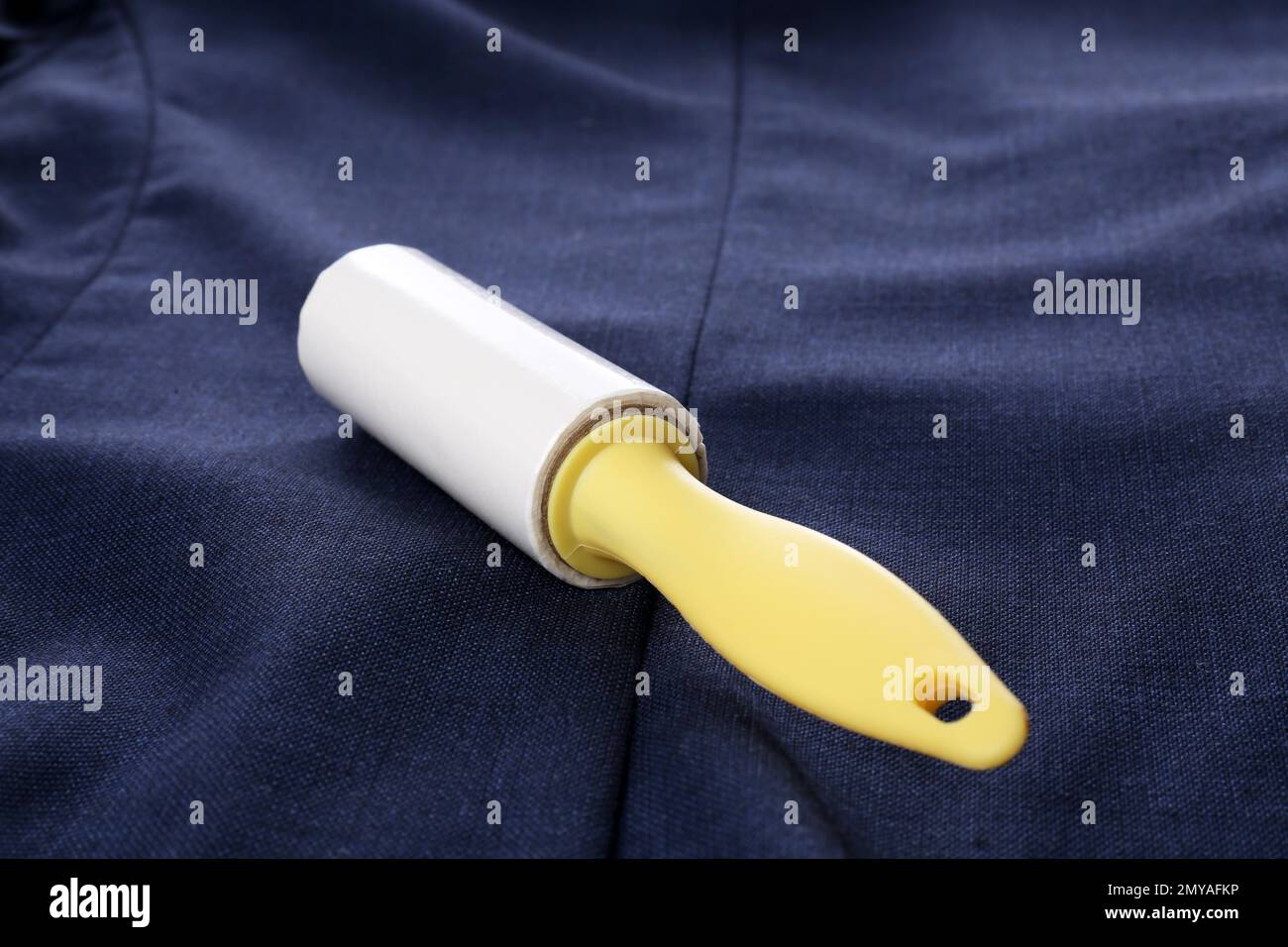 New lint roller with yellow handle on blue jacket Stock Photo