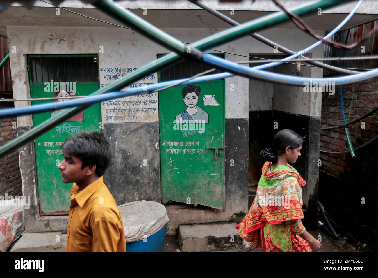 In this June 1, 2016 photo, Bangladeshis walk past a public toilet in a