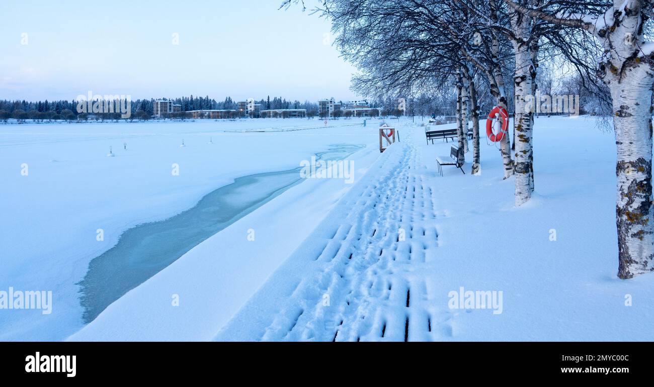 Snowy pier at the icy seaside. Red lifebuoy. Stock Photo