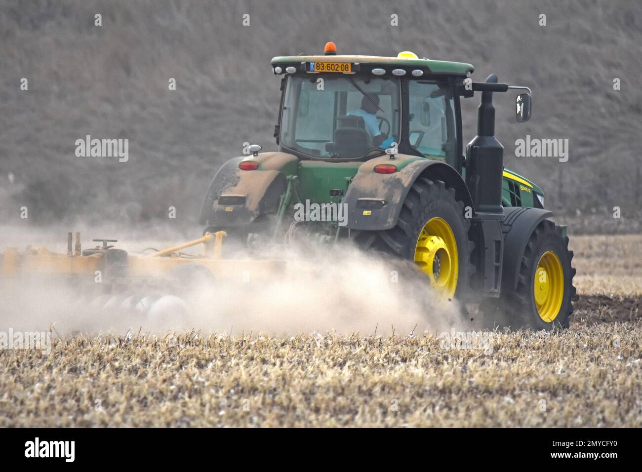 Tractor  plowing soil in dry field Stock Photo
