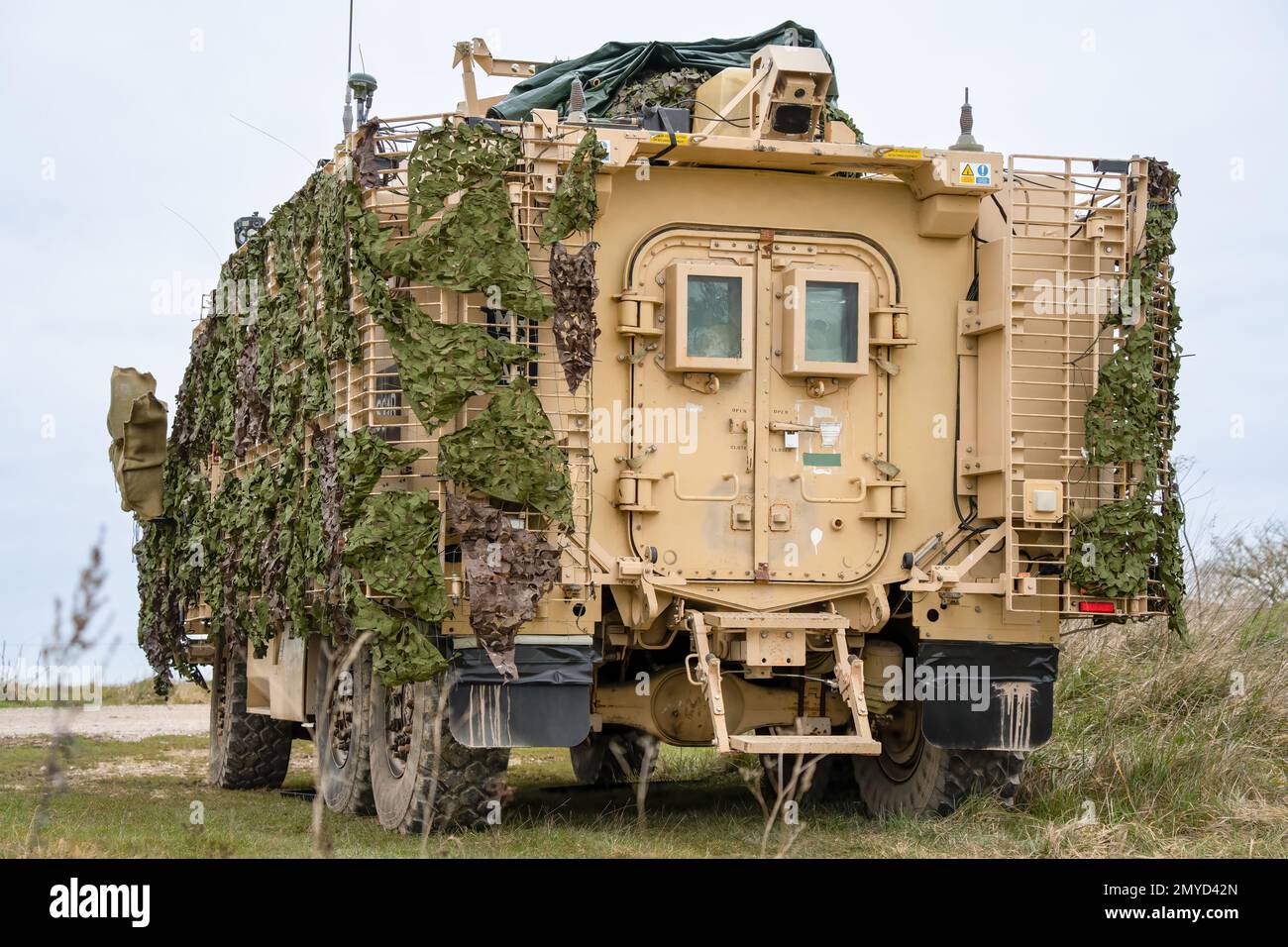 close-up of a British army Mastiff protected patrol vehicle under green camouflage netting Stock Photo