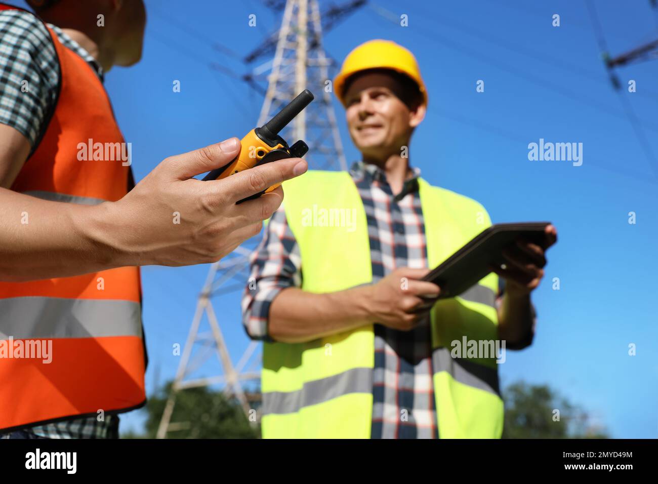 Professional electricians near high voltage towers, focus on hand with