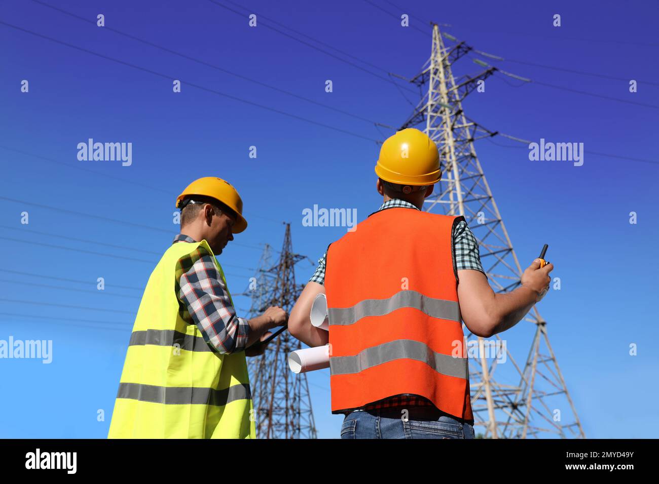 Professional electricians in uniforms near high voltage towers Stock