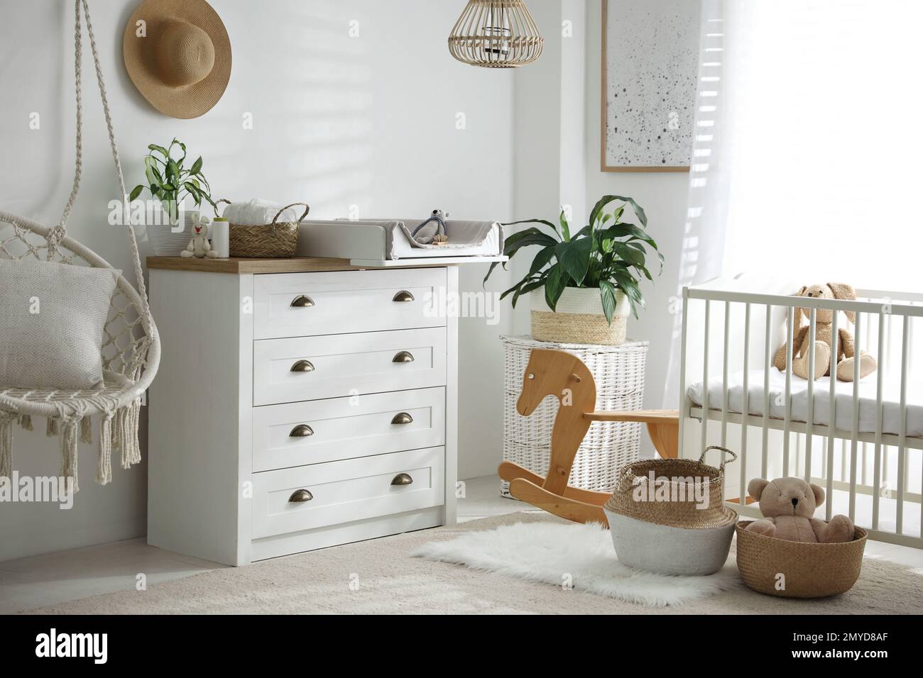 Chest of drawers with changing tray and pad near comfortable cradle in